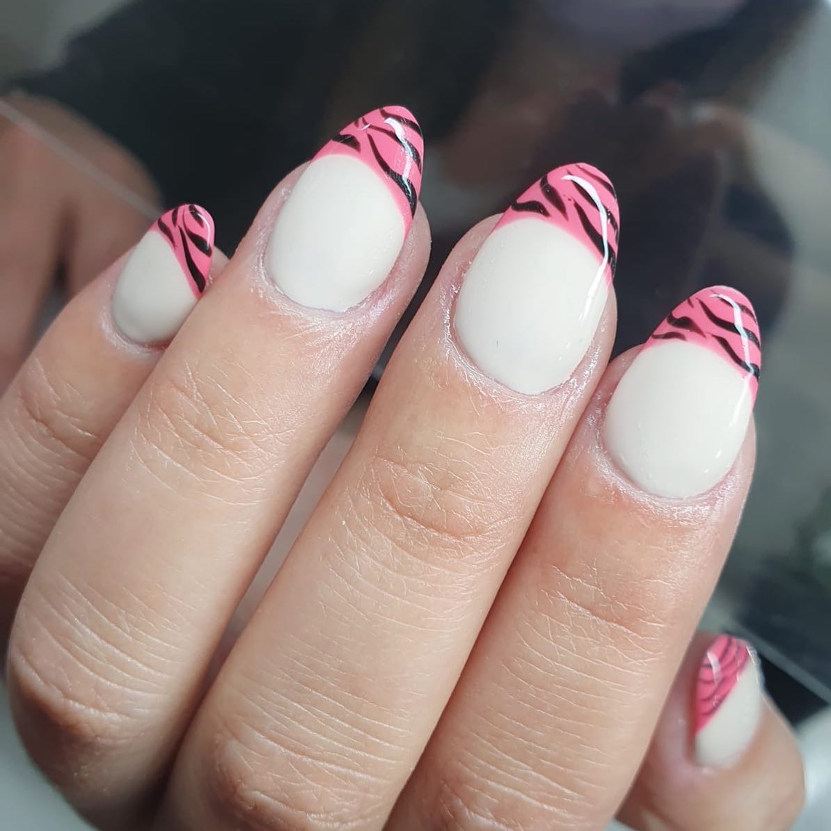 Uñas almendradas con base lechosa y french rosa con rayas negras de cebra pintadas a mano