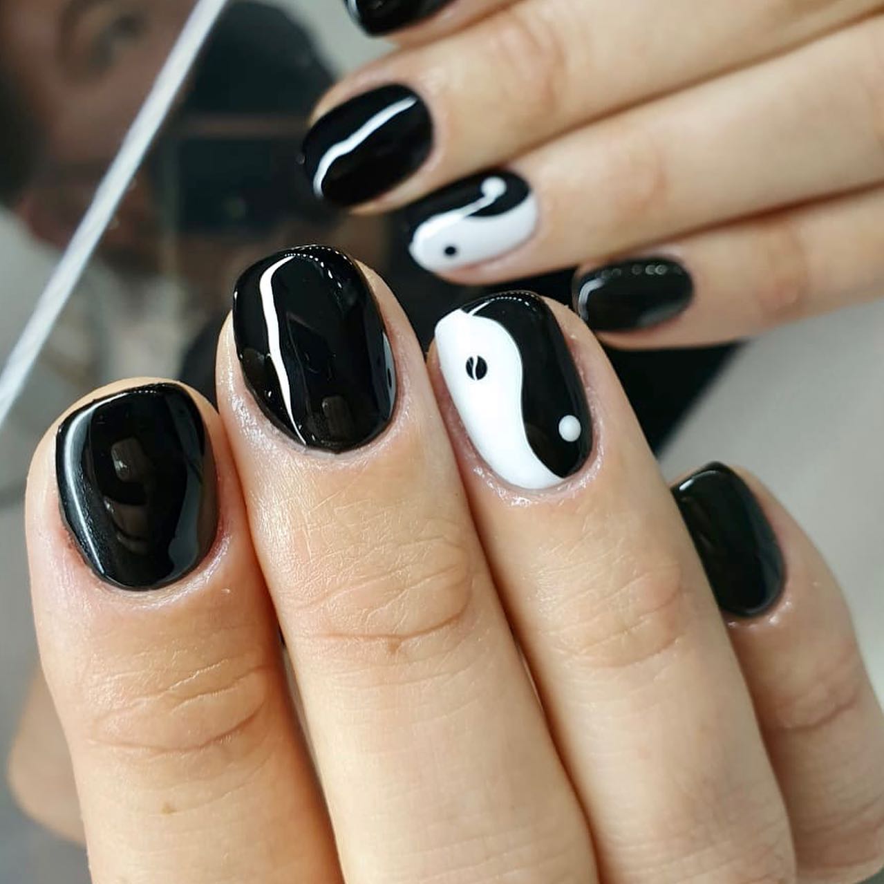 Uñas negras con brillo y una uña con un yin-yang blanco y negro pintado a mano